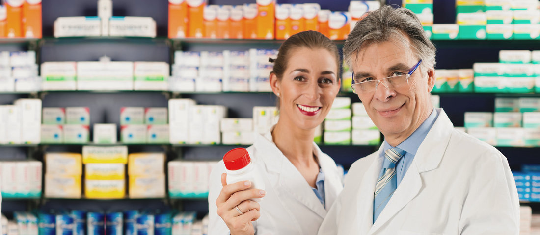 an old man pharmacist holding bottle medicine with young lady pharmacist