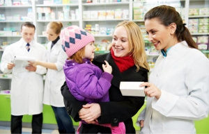 mother and pharmacist listening to a child and other pharmacists are on the background
